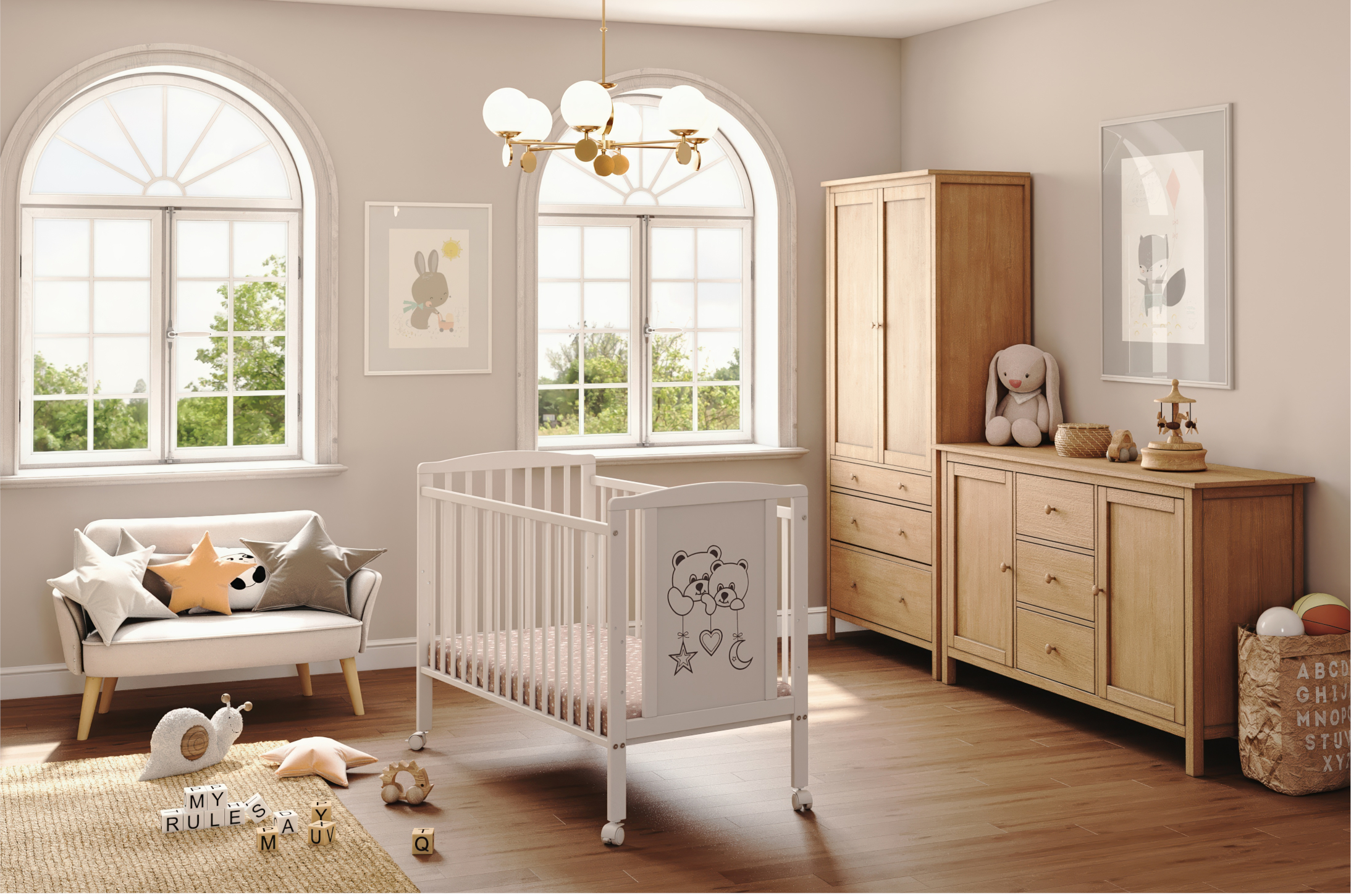 Białe łóżeczko dziecięce z dekoracyjnym frontem przedstawiającym dwa misie, ustawione w jasnym pokoju dziecięcym przy oknie. Łóżeczko stoi na kółeczkach i ma materac w środku.